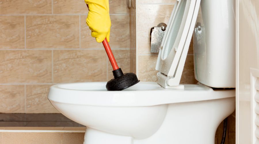 man using a plunger to unclog toilet